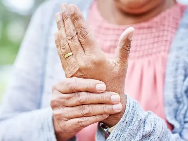 Person holding their wrist and hand with arthritis discomfort
