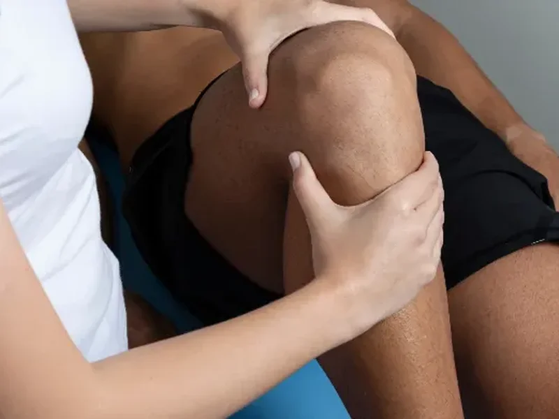 Physical therapist examining a patient's knee during an evaluation
