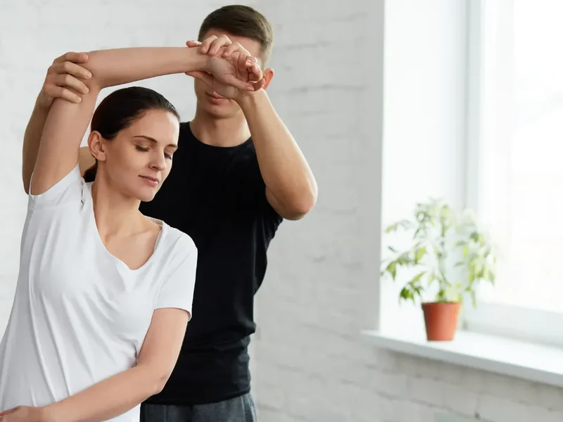 Physical therapist assessing a patient's shoulder mobility and rotator cuff strength