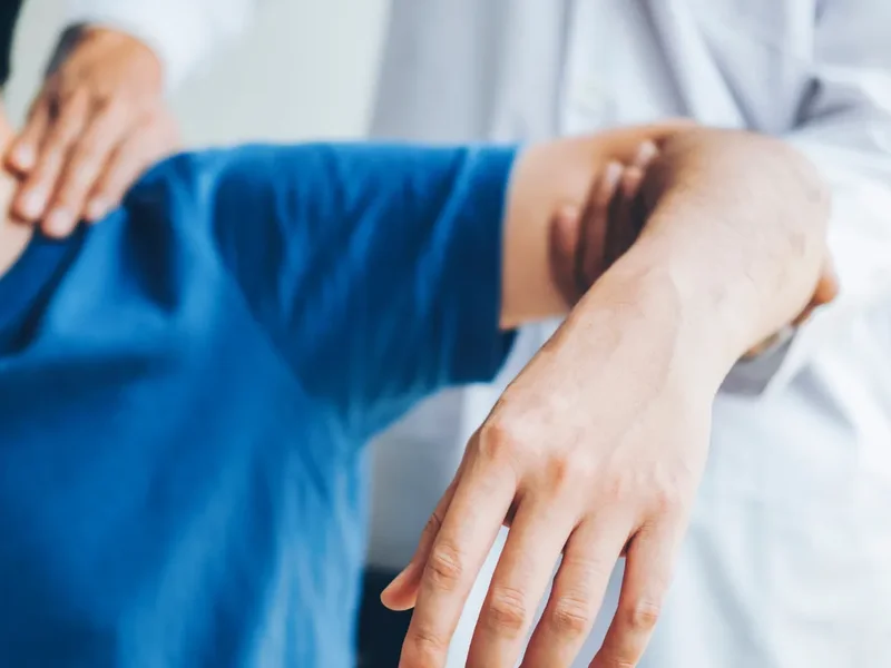 Physical therapist assessing a patient's shoulder mobility and strength