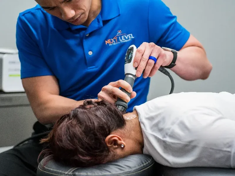 Dr. Jack Wong treating a patient's neck with a handheld therapy device