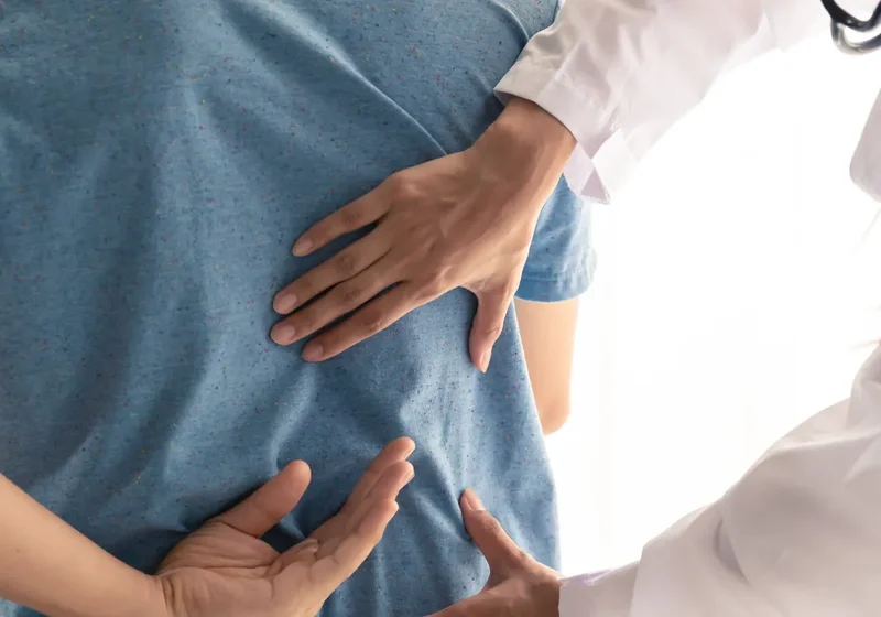 Clinician palpating a patient's back during an exam